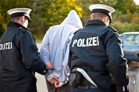 Polizisten führen Verdächtigen ab